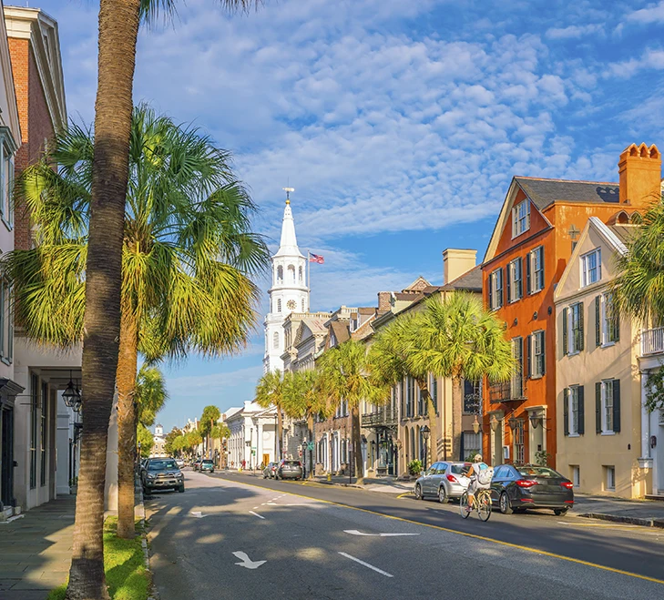 Charming street view with colorful historic buildings and palm trees under a blue sky, Charleston, South Carolina.